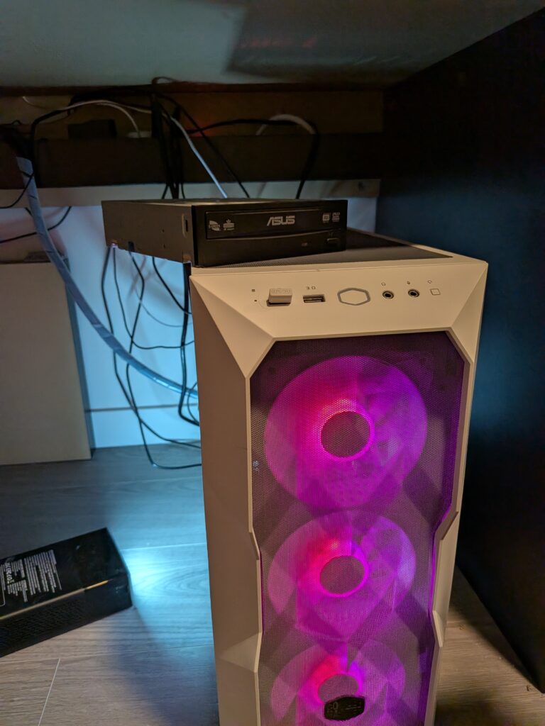 White computer tower with bright colour fan lights with a disk drive sitting on top