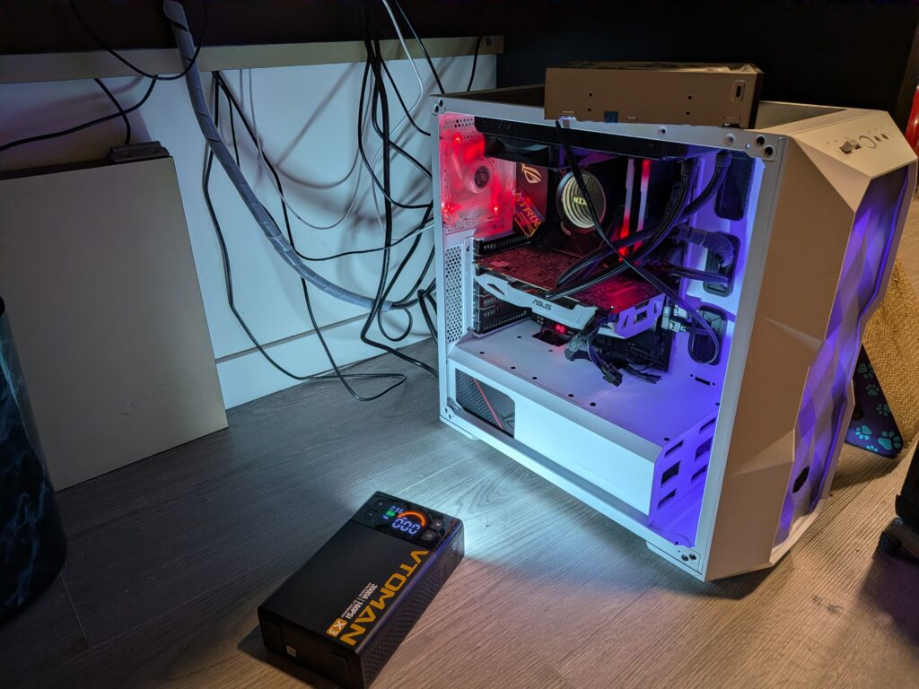 White computer tower case under desk sitting open illuminated by portable light