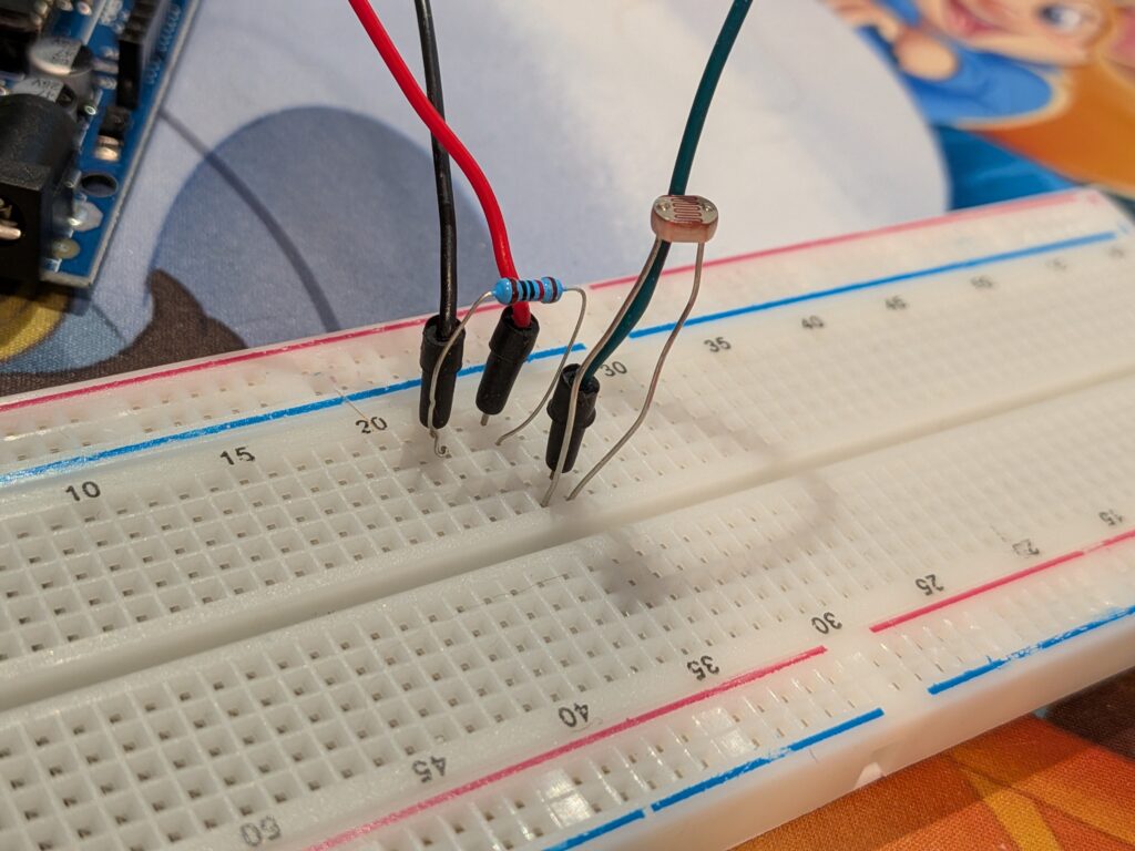 Breadboard with LDR and resistor connected with 3 wires directed to the Arduino Uno board.